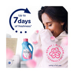 Person smelling a towel with a small Downy April Fresh bottle in the background and 'Up to 7 days of freshness' text