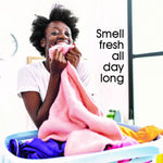 Person joyfully smelling a pink towel over a laundry basket with overlay text 'Smell fresh all day long'