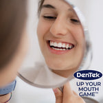 Person smiling into a handheld mirror with DenTek logo and ‘Up Your Mouth Game’ slogan in corner