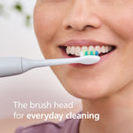 Close-up lifestyle image of a person smiling while a Philips Sonicare brush head contacts their front teeth