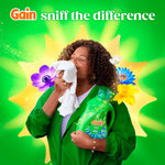 Person sniffing a cloth while holding a Gain Waterfall Delight bottle with floral accents and 'sniff the difference' text