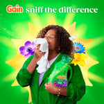 Lifestyle-style promo of a person smelling fabric while holding a Gain Moonlight Breeze detergent bottle with floral accents