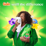 Person holding a Gain Happy Hibiscus bottle and smelling a cloth with floral illustrations and 'sniff the difference' text
