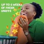 Smiling person sniffing an orange towel with yellow flower graphics and text ‘Up to 6 weeks of fresh sniffs’