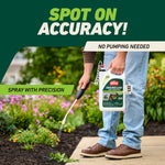 Person using Ortho GroundClear comfort wand to spray weeds along a landscaped bed and sidewalk