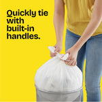 Person tying a white Glad Quick-Tie trash bag over a small metal wastebasket against a bright yellow background