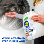 person holding a container of all free clear mighty pacs advanced oxi by a washer while placing one pac inside