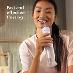 Person using a Philips Sonicare compact flosser in a bathroom, smiling while holding the device to their mouth.