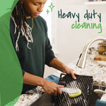 Person using a Scotch-Brite dishwand to scrub a grill pan at a kitchen sink, text reading ‘Heavy duty cleaning’.