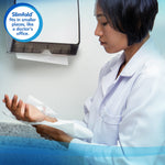Person in a lab coat using Scott paper towels from a wall dispenser; inset badge notes Slimfold fits smaller spaces