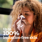 Person holding a tissue to their nose with eyes closed and text claiming up to 100% irritation-free skin