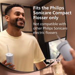 Smiling person looking into a mirror while holding a Philips Sonicare compact flosser, with text about device compatibility.