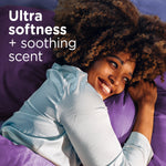 Smiling person hugging a purple pillow with overlay text ‘Ultra softness + soothing scent’