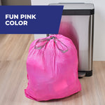 Drawstring-tied full pink trash bag sitting on wood floor beside a stainless step trash can with 'Fun Pink Color' banner