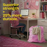 Room scene with a pink trash bag full of laundry beside a desk and overlay text claiming superior strength and 25% more durable