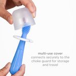 Hands placing a translucent multi-use cover over the head of a blue silicone baby toothbrush, with caption text