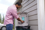 Person placing a corrugated FlyPad trap inside the lid of an outdoor trash can to stick to the plastic surface