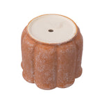 Upside-down terracotta scalloped planter showing the bottom surface with a drainage hole and a small plug.