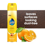 Yellow Pledge aerosol can with orange graphic next to sliced oranges and wood background reading 'leaves surfaces looking dust-free'