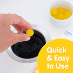 Hand dropping a small yellow Plink disposal tablet into a sink drain with a ramekin of additional tablets visible