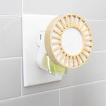 A plug-in diffuser with a yellow decorative cover and an aroma oil refill bottle attached to a wall outlet