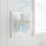 Plug-in diffuser inserted in a wall outlet releasing stylized pale blue fragrance vapor over a bottle of blue oil