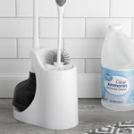 Plunger and toilet brush stored in a white plastic caddy placed on a floor next to a bottle of Great Value clear ammonia cleaner