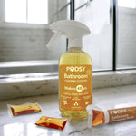 Podsy Bathroom foaming cleaner bottle with orange label on a bathroom counter with refill pods nearby.