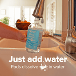 Hand holding an empty Podsy Glass Cleaner bottle under a kitchen faucet with text overlay