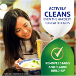 Woman eating noodles with overlay text 'Actively cleans even the hardest to reach places' and icon stating 'Removes stains and plaque build-up'