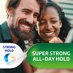 Smiling couple eating with a Poligrip branded green banner proclaiming super strong all-day hold.