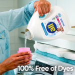 Person pouring liquid from an all baby detergent bottle with pink cap into a pink measuring cup over a washing machine