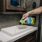 Person pouring Camco TST lemon-scented deodorizer into an RV sink basin in a bathroom setting
