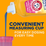 Close-up of detergent being poured from a yellow Arm & Hammer bottle into a pink measuring cup against an orange background