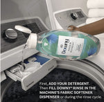 A hand pouring Downy Rinse & Refresh Cool Cotton into the fabric softener dispenser of a washing machine.