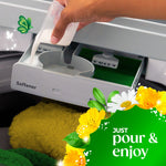Hand pouring liquid fabric softener into washing machine dispenser with floral Gain graphic and pouring instruction text