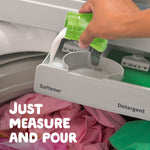 Hand pouring white liquid fabric softener into a washer dispenser labeled softener over laundry