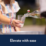 Person pouring a clear drink into a Chinet Crystal clear plastic cup held by another person outdoors