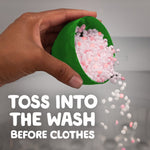 Hand pouring small pink and white scent-bead pellets from a green measuring cap with instructional text overlay