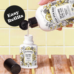 Hand pouring Poo-Pourri refill liquid from a large bottle into a smaller travel-size bottle against tiled background with 'Easy Refills' badge.