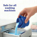 Hand pouring light blue liquid fabric softener from a blue measuring cap into a washing machine dispenser drawer