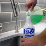 Pouring green cleaning solution from a larger jug into a Zep Professional spray bottle at a kitchen sink