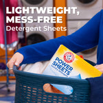 Laundry scene showing a person carrying a basket with an ARM & HAMMER Power Sheets box and text 'Lightweight, Mess-Free Detergent Sheets'.