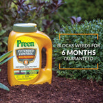 Preen Extended Control yellow container sitting on mulch beside shrubs with text claiming it blocks weeds for six months.