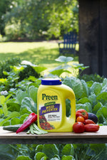 Preen Natural Vegetable Garden Weed Preventer jug displayed outdoors on a bench with vegetables and leafy garden background