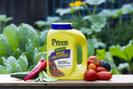 Preen Natural Vegetable Garden Weed Preventer container staged with fresh tomatoes and peppers on a wooden plank in a garden