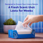 Hand pulling a translucent dryer sheet from an open retail box with text about a fresh scent that lasts for weeks