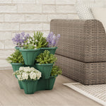 Stacked hunter green three-tier planter filled with flowers placed beside woven outdoor seating on a patio