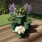 Hunter green three-tier stacking planter filled with assorted flowers on a wooden patio surface