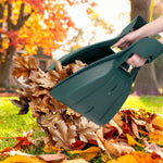 Hands holding green plastic leaf scoops scooping a colorful pile of fallen autumn leaves in a yard scene.